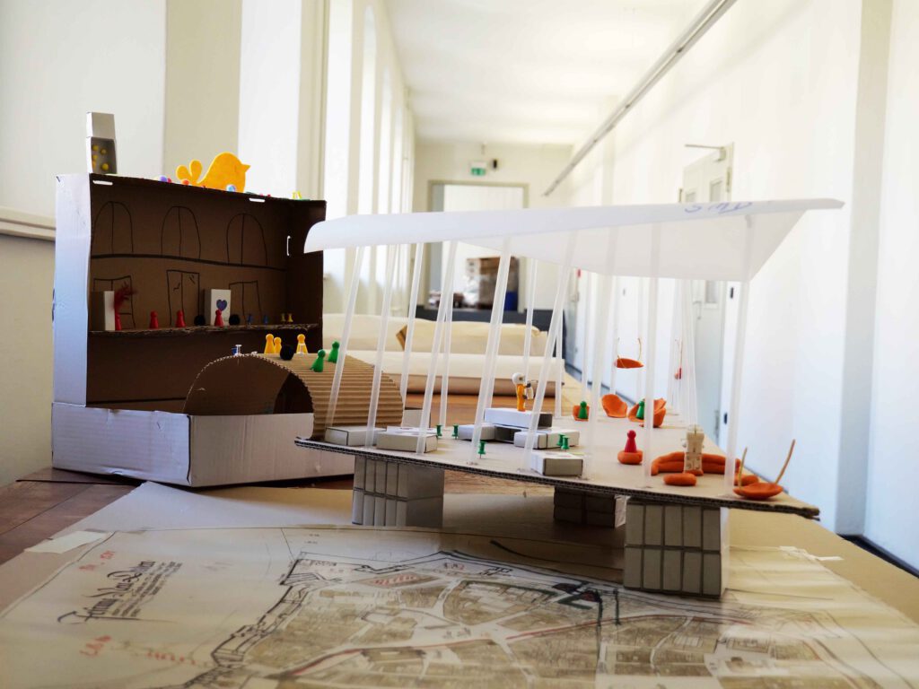 Zu sehen sind selbstgebaute Modelle aus verschiedenen Materialien, wie zum Beispiel bunten Lego-Spielsteinen oder Pappe. In den Modellen gibt es Figuren, die Museumsbesucher verkörpern sollen. 